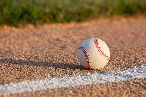 Low angle selective focus view of a baseball on a basepath with a white stripe