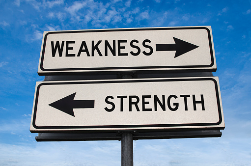 Road sign with words weakness and strength. White two street signs with arrow on metal pole. Directional road, Crossroads Road Sign, Two Arrow. Blue sky background