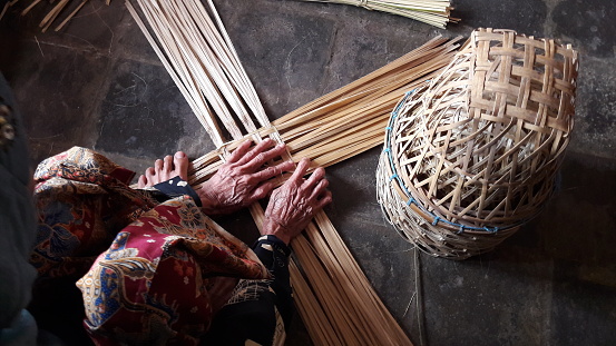 An old woman's hand makes plaits from bamboo, in Sukabumi, West Java, Indonesia