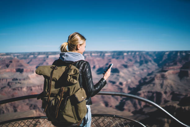 istock Woman with backpack using smartphone in Grand Canyon 1301939569