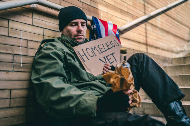 homeless war veteran with alcohol bottle and cardboard - depression sadness usa american flag imagens e fotografias de stock