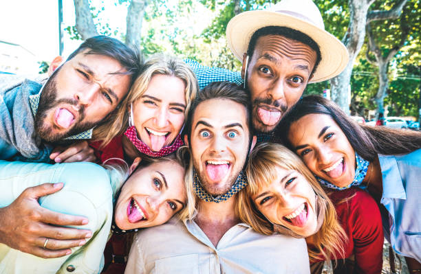 istock Multicultural friends taking crazy selfie sticking out tongue during Covid 19 third wave - New normal lifestyle concept with young milenial people having fun together - Bright azure sunshine filter 1301942479