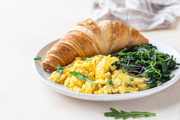 istock Croissant served with scrambled eggs and spinach on plate, light concrete background. Breakfast. 1301943519