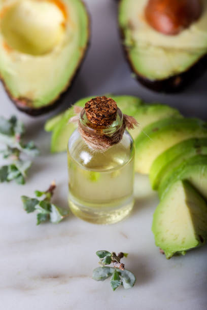 bottiglia di olio di avocado con avocado fresco su sfondo marmo bianco. - luxury milk dinner glass foto e immagini stock