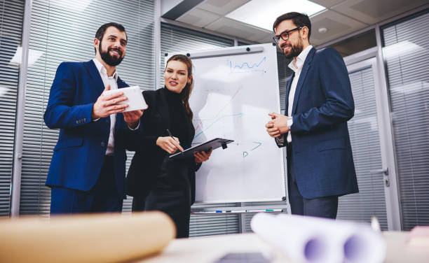 istock Confident male and female employees using office internet connection for browsing financial website and checking exchange news via modern touch pad, Caucasian colleagues collaborating on board room 1301943983