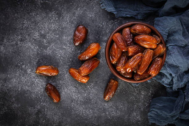 istock Dried date fruit in bowl on wooden background. Delicious dates fruit. Top view 1301944926
