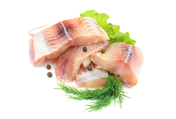 Pangasius fish fillet, pieces on a green lettuce leaf. Isolated on a white background. Fresh Fish Fillet. Pangasius fish fillet, pieces on a green lettuce leaf. Isolated on a white background. Fresh Fish Fillet.The view from the top catch of fish stock pictures, royalty-free photos & images