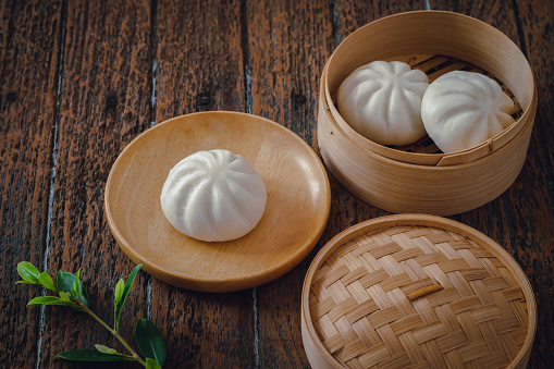 Steamed pork buns on wooden plate and bamboo steamer, Chinese dim sum