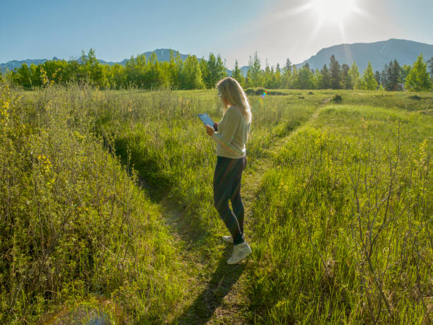 女性ハイカーは緑の山の牧草地を通ってパスをたどります - footpath field nature contemplation ストックフォトと画像