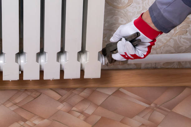 istock a plumber screws a cast-iron radiator to the heating system 1301952285