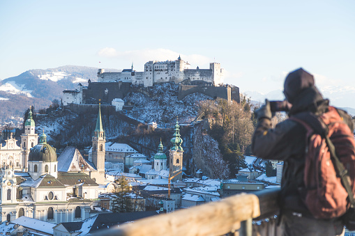 Young tourist man is making a photo of Salzburg with her smartphone, winter time