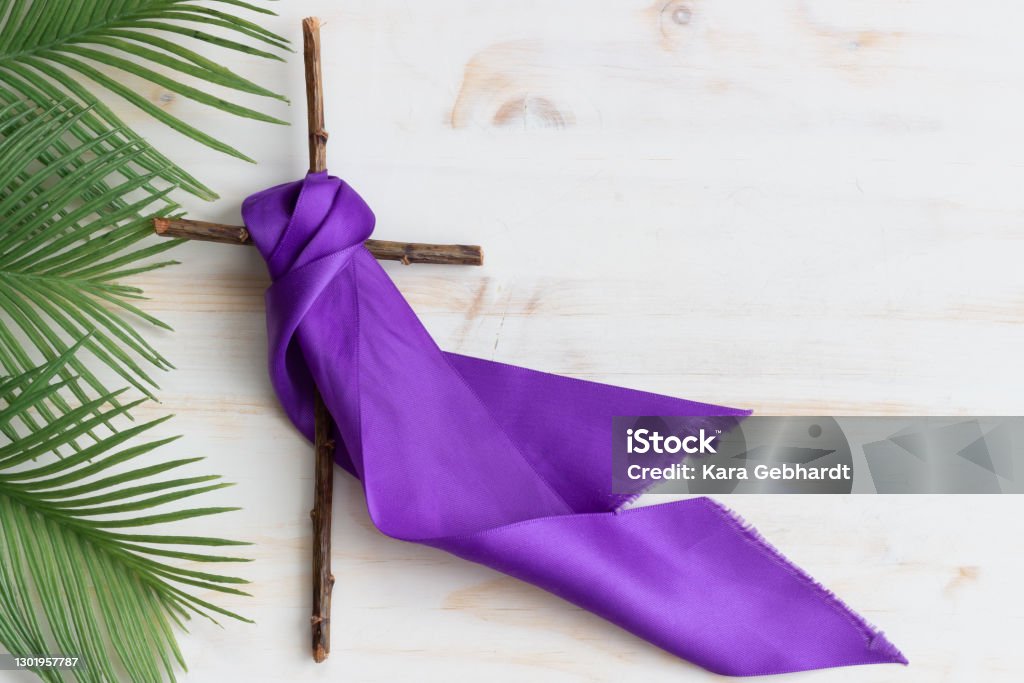 Wood cross with purple ribbon and palm leaves Wooden Christian cross with purple ribbon and palm leaves for lent or Palm Sunday on white wood background with copy space Lent Stock Photo