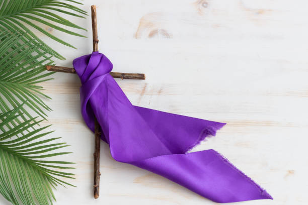 Wood cross with purple ribbon and palm leaves Wooden Christian cross with purple ribbon and palm leaves for lent or Palm Sunday on white wood background with copy space lent stock pictures, royalty-free photos & images