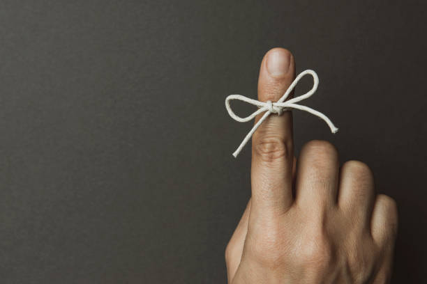 string bow tied on index finger - reminder memories human finger string imagens e fotografias de stock