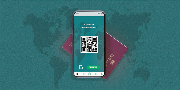 Flat lay, top view of a passport and a smart phone with a digital illustration of a Covid-19 Health Passport concept. Travel concept during the Covid-19 pandemic.