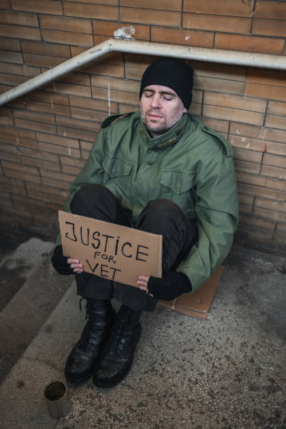 istock Homeless army veteran begging holding a placard 1301962775