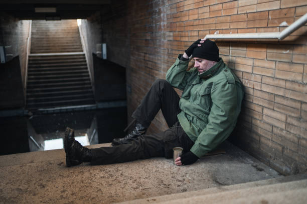 istock Homeless army veteran sitting on pavement begging 1301963023