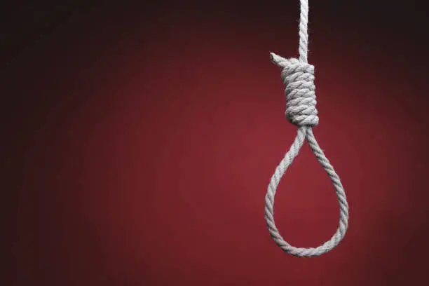 rope in shape of gallows hangs on red background. concept of depression, hopelessness, and suicide.