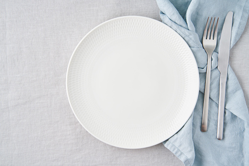 Serving a festive table. Beautiful plates and cutlery, flowers in vases on a wooden table.