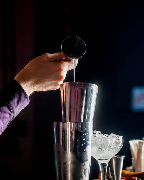 istock barman pours a cocktail into a shaker. Cocktail making and mixology 1301967490