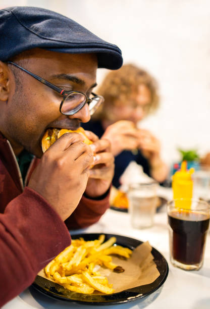 istock Young man sitting at a diner table eating a juicy cheeseburger 1301970660