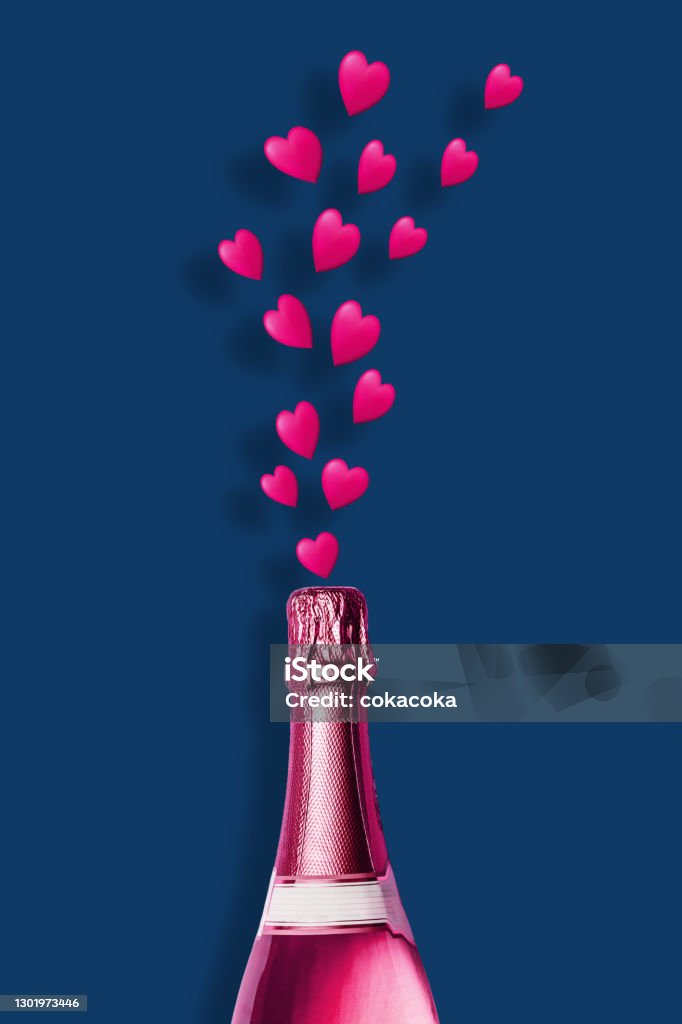 Pink champagne bottle Pink champagne bottle explosion with pink hearts on blue background minimal concept celebration idea Bottle Stock Photo