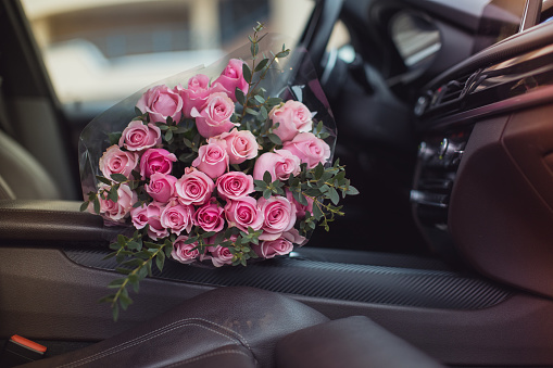 Big bouquet of beautiful fresh pink roses in luxury car. Valentines day romantic