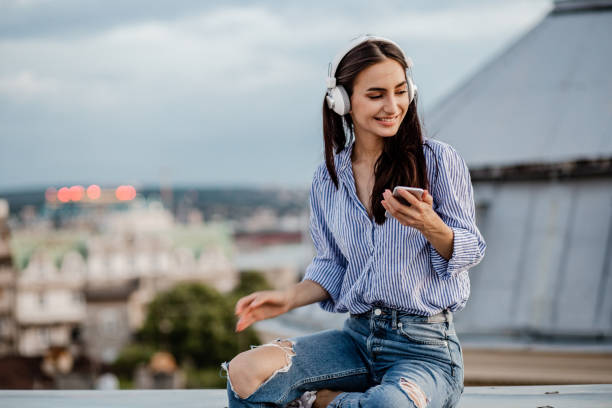 istock Young woman enjoying on the rooftop and using mobile phone 1301978063