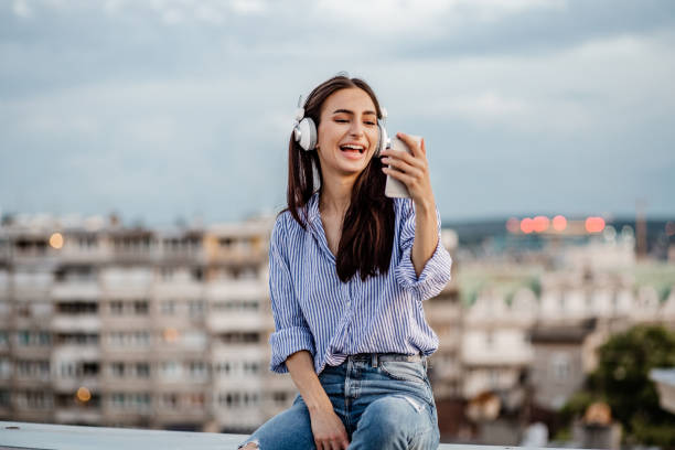 istock Young woman enjoying on the rooftop and using mobile phone 1301978615
