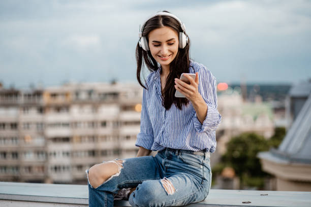 istock Young woman enjoying on the rooftop and using mobile phone 1301978623