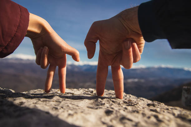 gestes de doigt homme et femme retiennent des mains et regardent des montagnes neige-couvertes - men suit holding human finger photos et images de collection