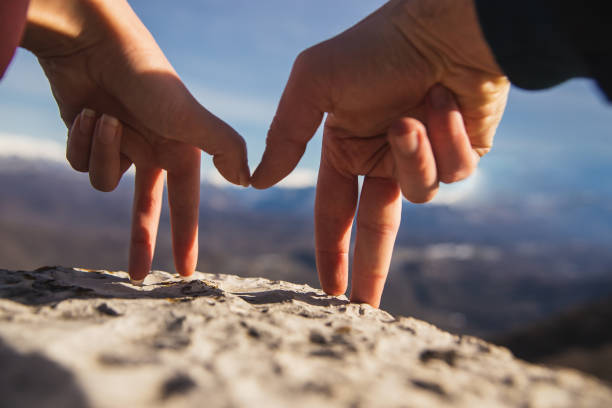 gestes de doigt homme et femme retiennent des mains et regardent des montagnes neige-couvertes - men suit holding human finger photos et images de collection