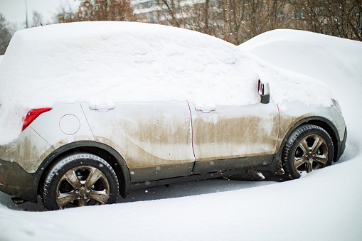 The car is covered with snow after a heavy snowfall, close-up. Car wipers up. Snow cyclone.