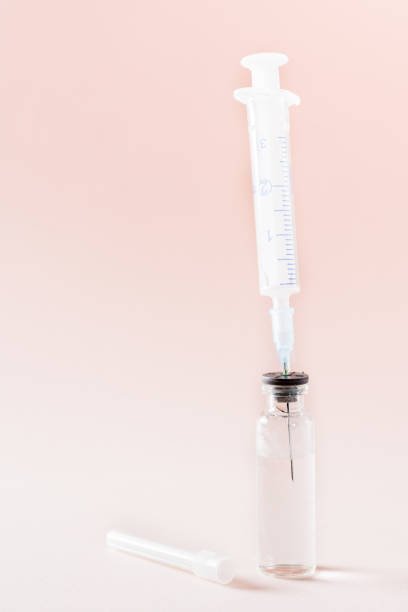 istock Vaccination and Immunization. Syringe needle inserted into a glass vial with vaccine. Vertical view 1301984791