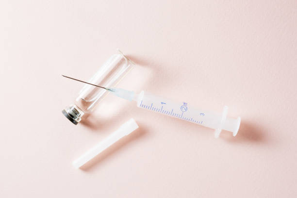 istock Vaccination and Immunization. Opened syringe on a glass vial with vaccine. Top view 1301984985