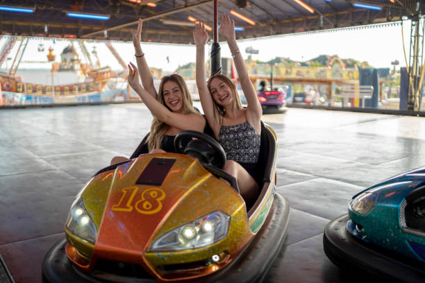 istock Two young girlfriends are laughing and shouting while riding a bumper car at amusement park 1301989197