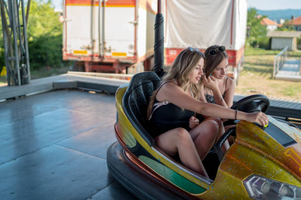 istock Two young girlfriends are laughing and shouting while riding a bumper car at amusement park 1301989250