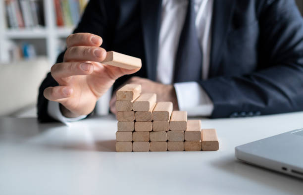 istock Businessman hand pulling out or placing wood block on the tower and semi-pyramid in modern office. Plan and strategy in business. 1301990428