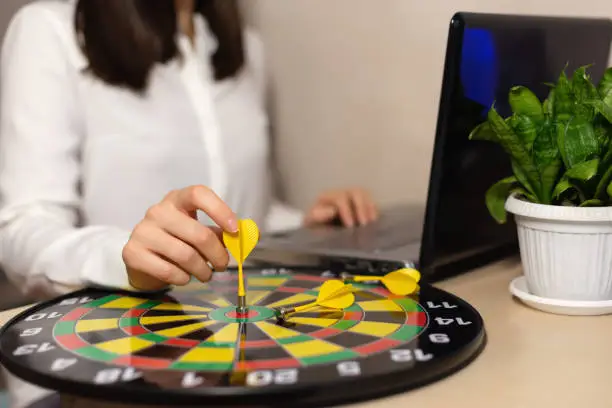 Close up hand of business woman holding dart on target to successful goal on table, success and achievement, winner and win concept