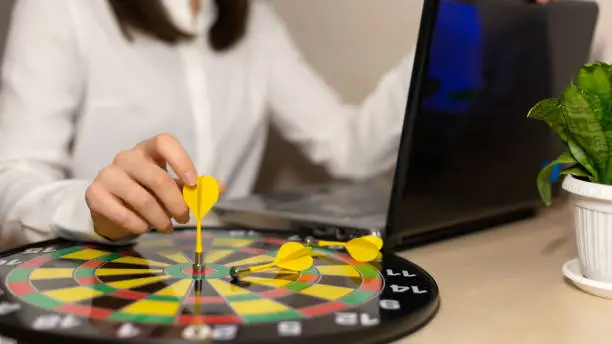 Close up hand of business woman holding dart on target to successful goal on table, success and achievement, winner and win concept