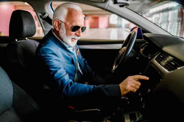 Senior businessman turning on his car radio while driving Photo of a senior turning on his car radio while driving old person listening to radio stock pictures, royalty-free photos & images