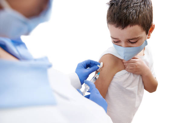 istock Scared boy looks at his hand while doctor vaccinating him. Isolated on a white background 1301994700