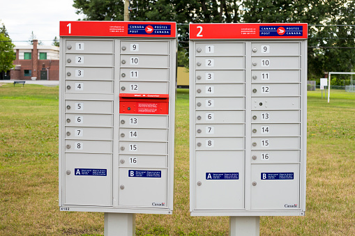 Ottawa, Canada - July 20, 2020: Canada Post mail boxes set in the neighborhood community near park with red sign in English and French