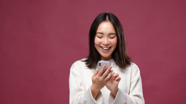 Young asian cheerfull woman scroll phone against marsala copyspace