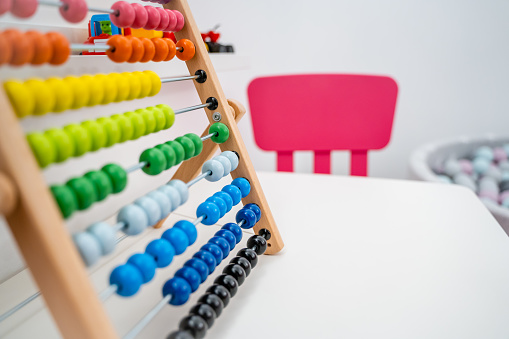 Colorful Abacus on Table with Pink Chairs and Ball Pool in Background, Modern Nursery or Children's Playroom