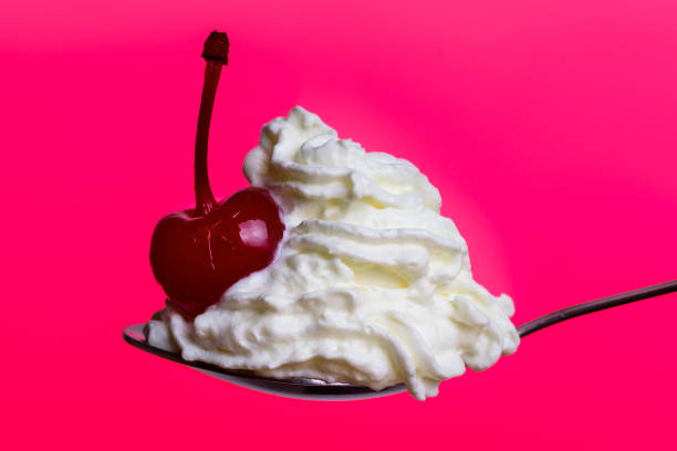 istock Whipped cream with maraschino cherry on pink background 1302000396
