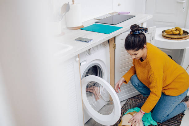 istock Young woman putting dirty laundry into washing machine 1302001845