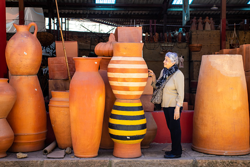 Senior woman looking at big plant pots in the small town of Raquira. The City of Pots, Colombia