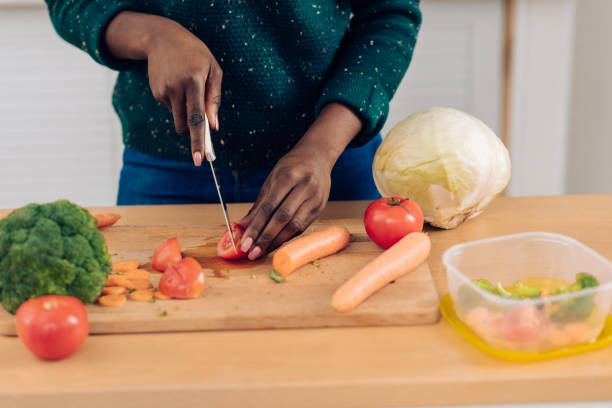 istock Unrecognizable African American woman chopping veggies and packing it in plastic boxes 1302001987