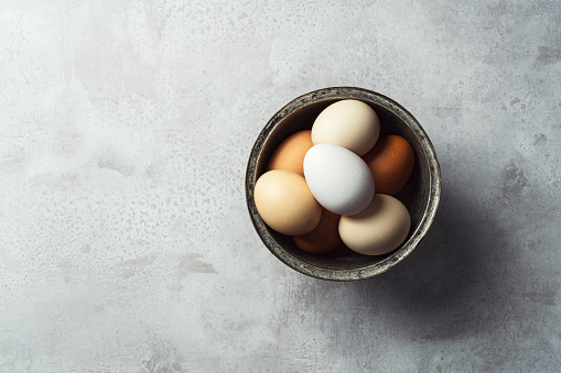 Color gradient brown eggs in a bowl on gray rustic background